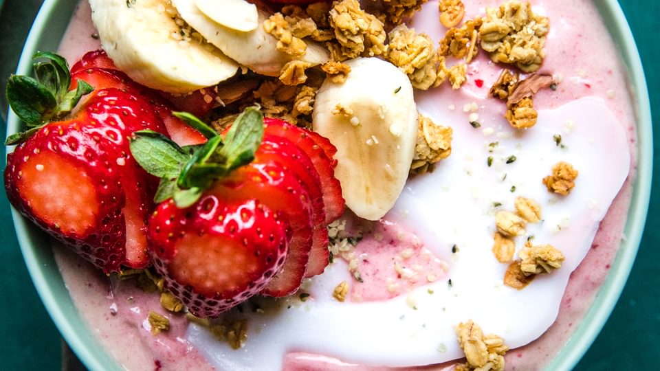 Homemade smoothie bowl topped with strawberries, bananas, granola and coconut oil
