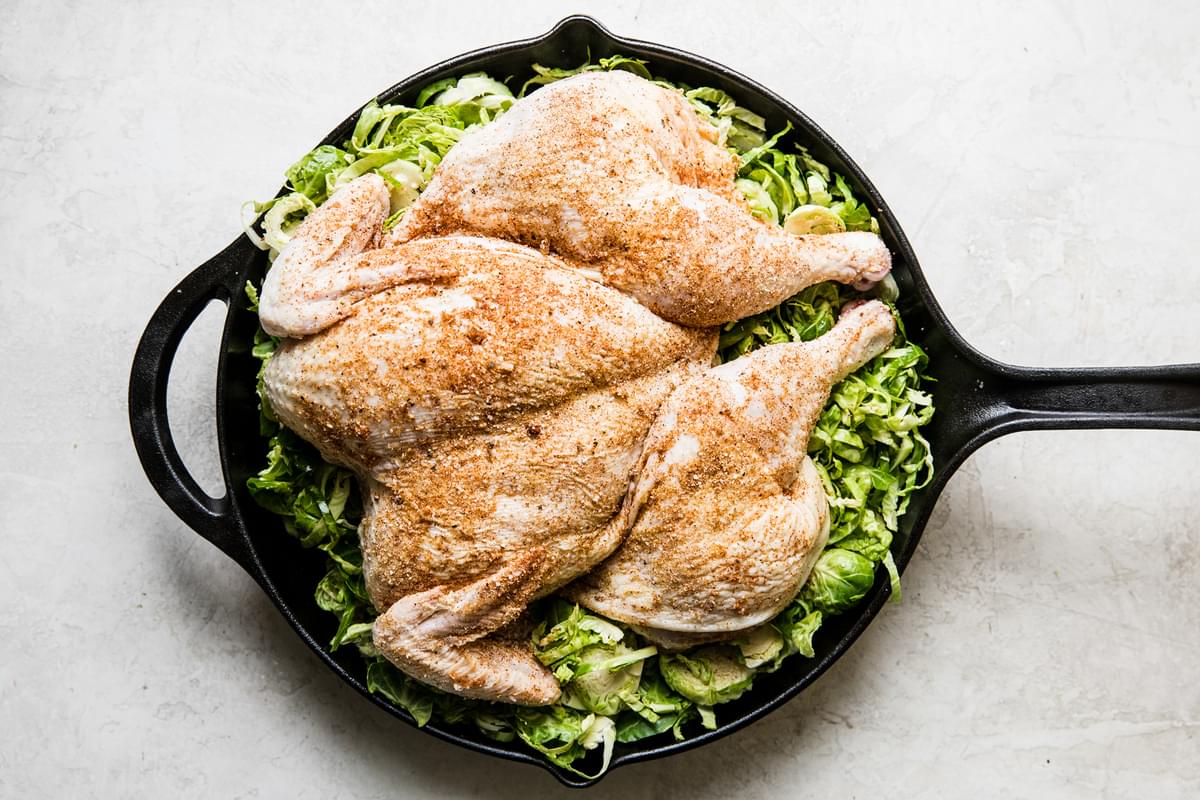 spatchcocked chicken on top of shaved Brussel sprouts in a cast iron skillet
