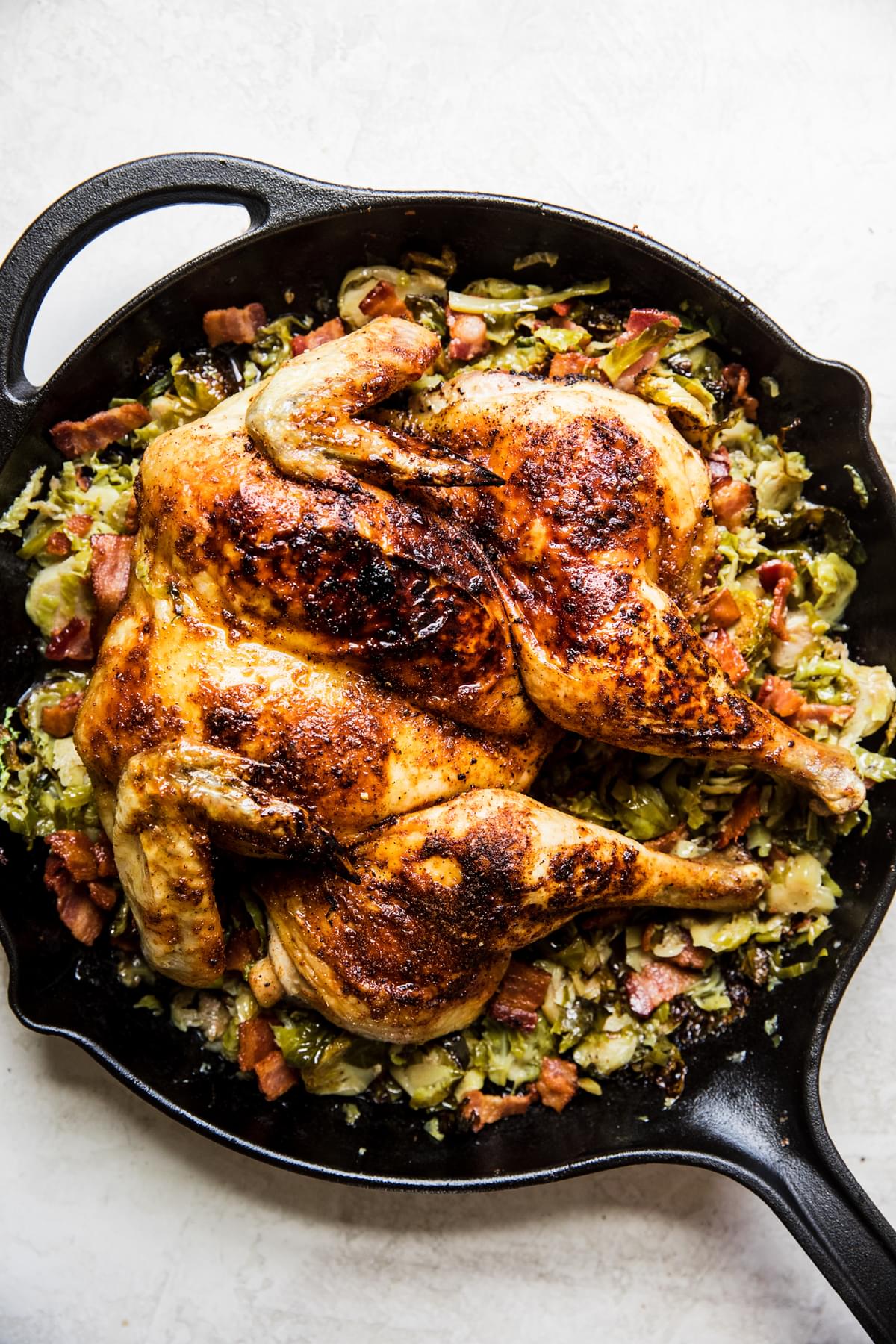 spatchcocked roast chicken on top of shaved brussels sprouts in a cast iron skillet