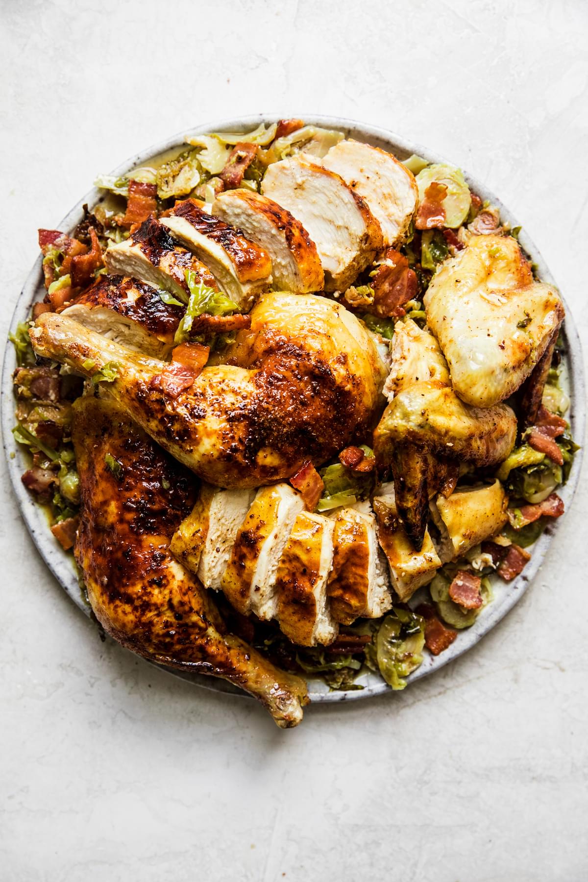 sliced spatchcocked roast chicken on top of shaved brussels sprouts on a serving platter