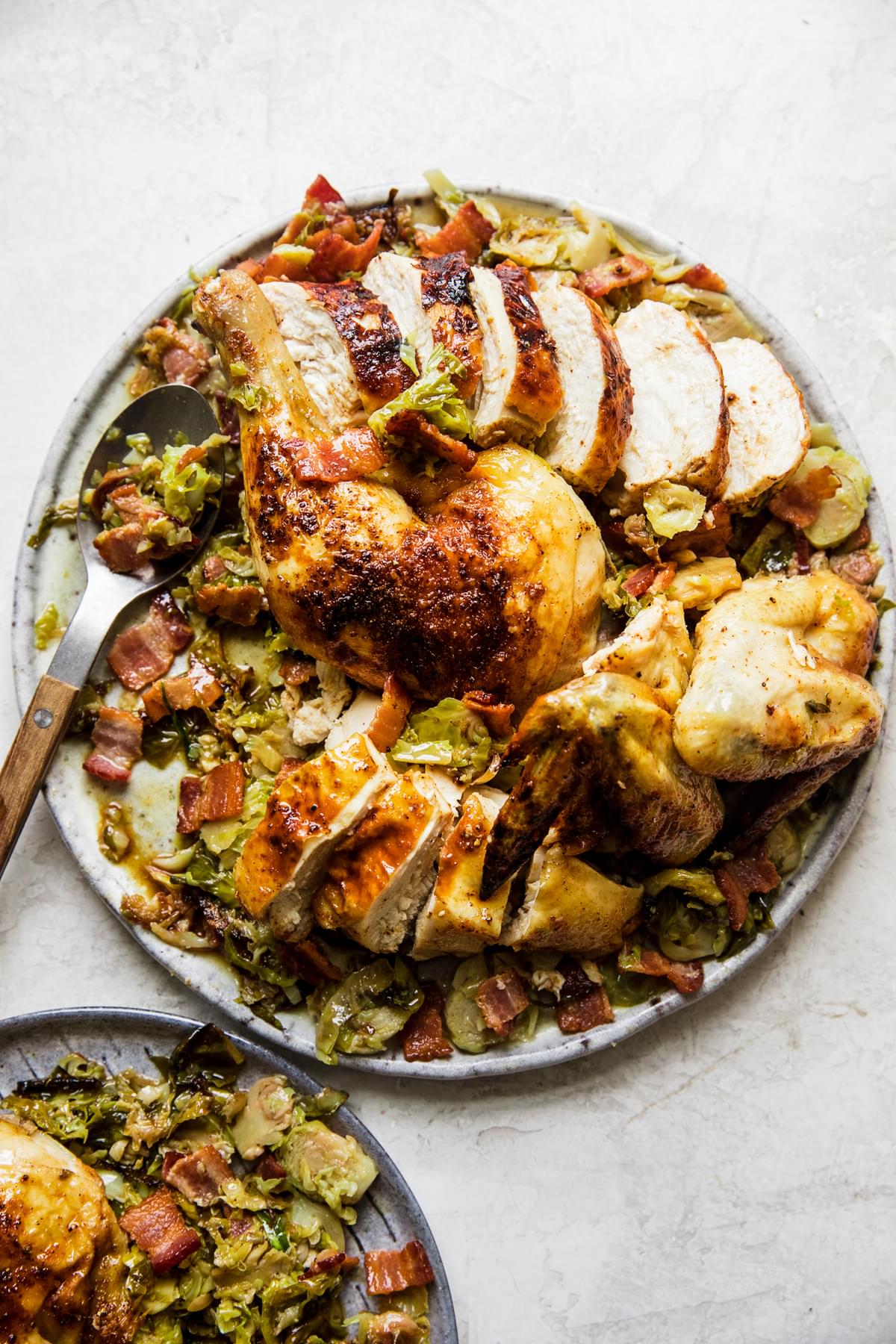 sliced spatchcocked roast chicken on top of shaved brussels sprouts on a serving platter