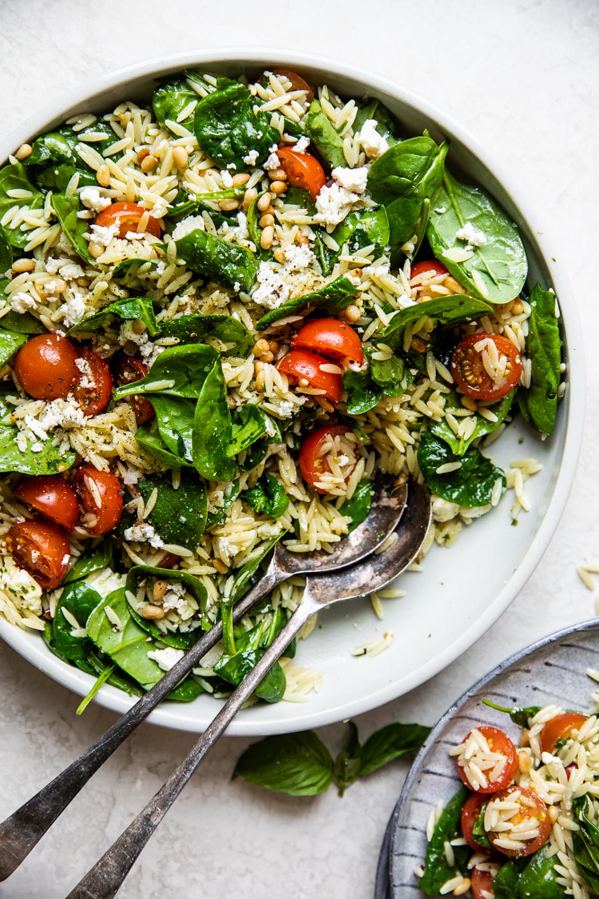 baby spinach, cherry tomatoes, feta, orzo, pine nuts and basil in a bowl