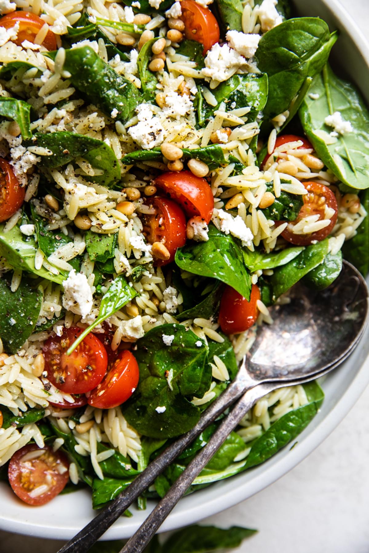 baby spinach, cherry tomatoes, feta, orzo, pine nuts and basil in a bowl