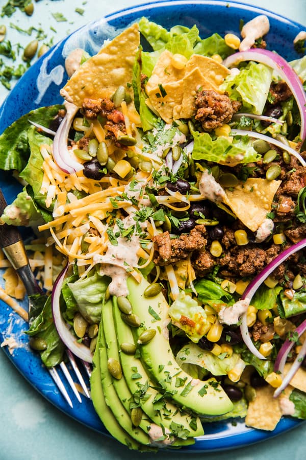 Homemade taco salad on a plate with ground beef, avocado and tortilla chips