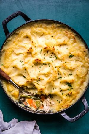 Homemade Turkey Shepherd's Pie in a cast iron skillet  being scooped with a spoon