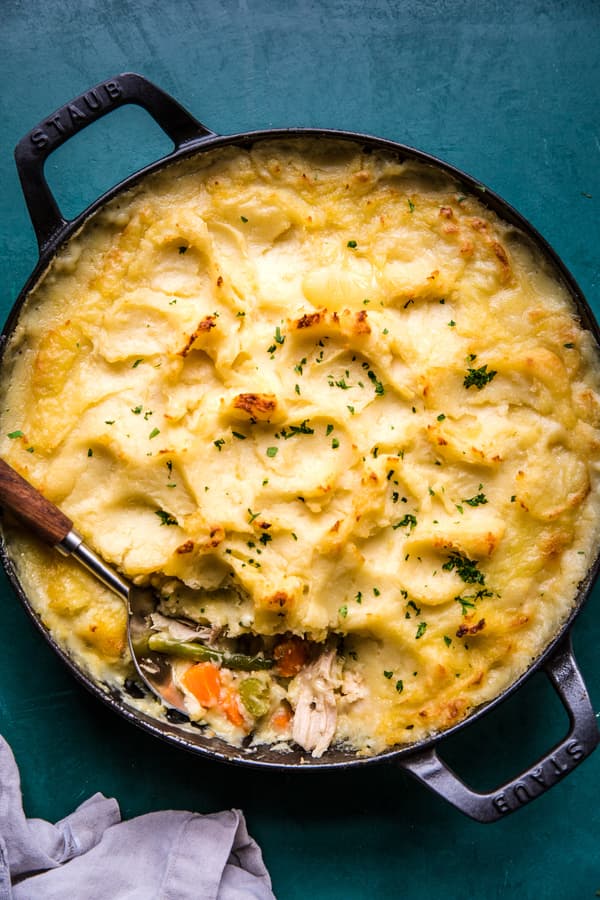 Homemade Turkey Shepherd's Pie in a cast iron skillet  being scooped with a spoon