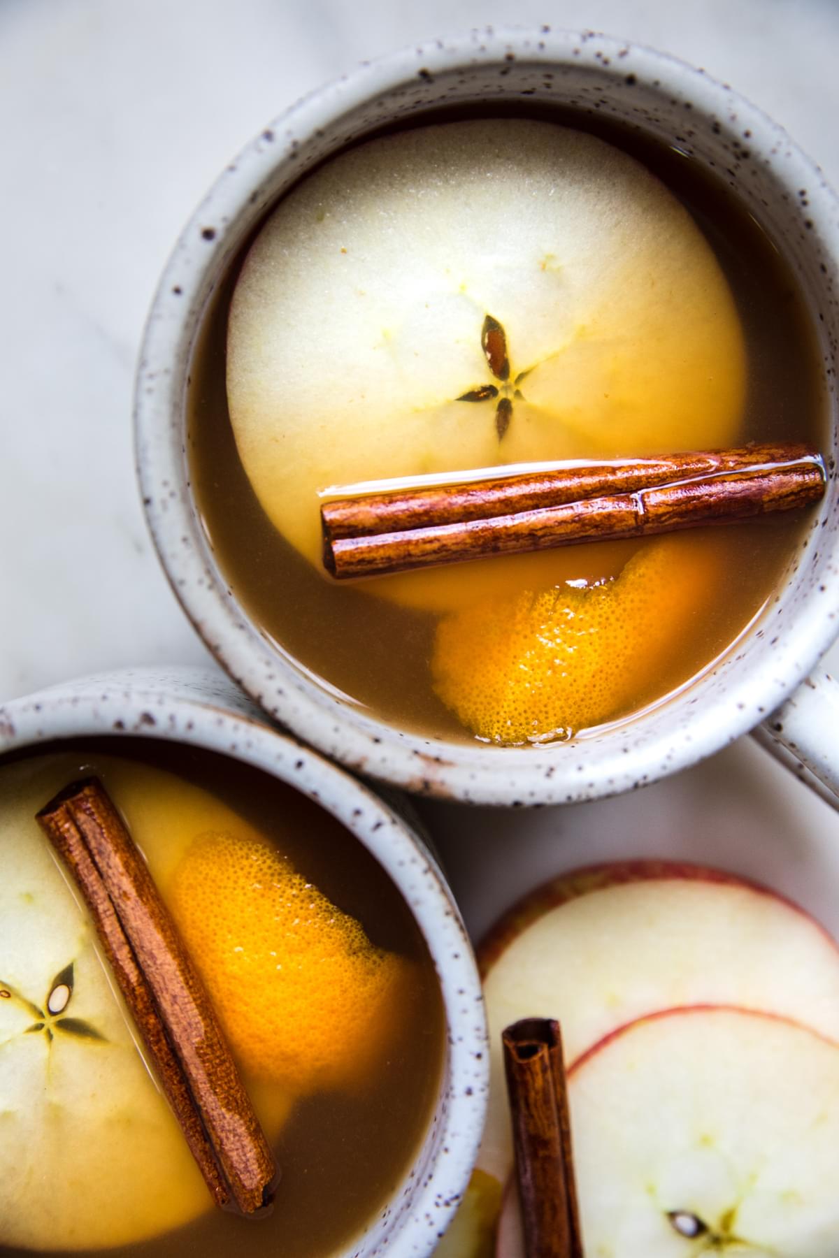 homemade wassail in mugs garnished with apple slices and cinnamon sticks
