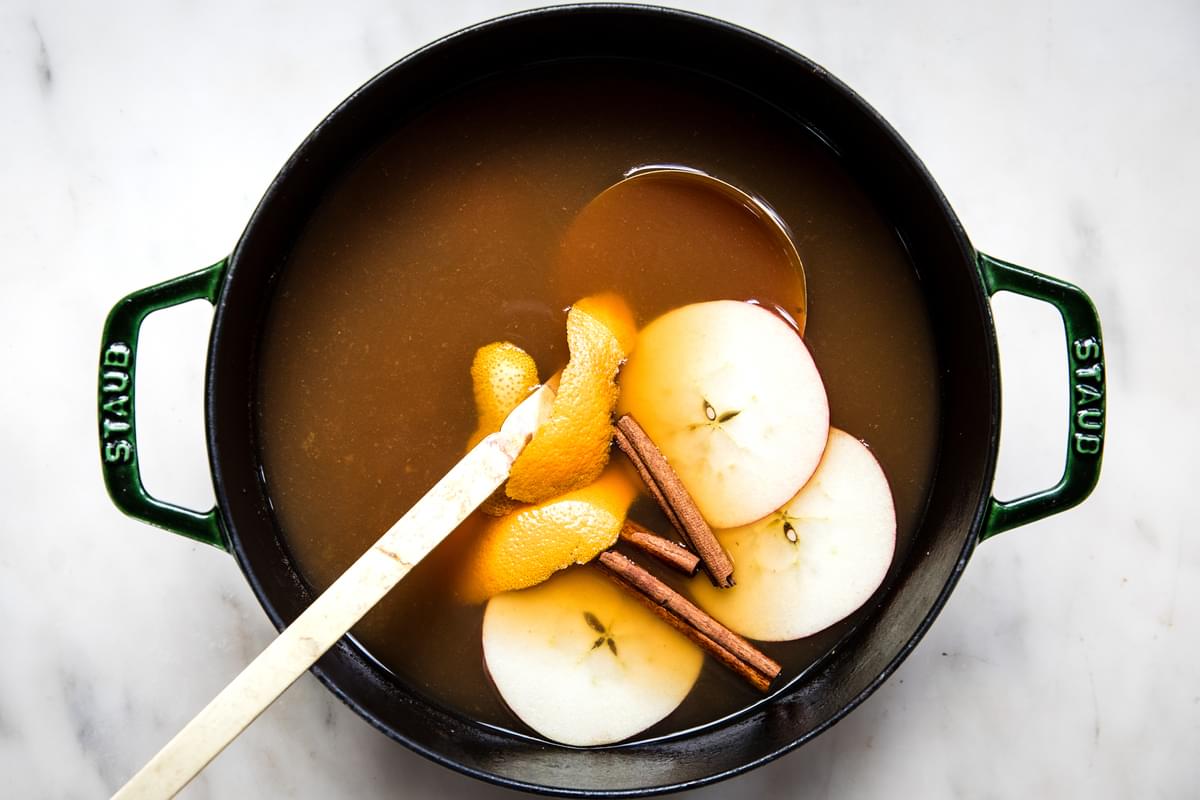 homemade wassail in a pot with sliced apples and a ladle