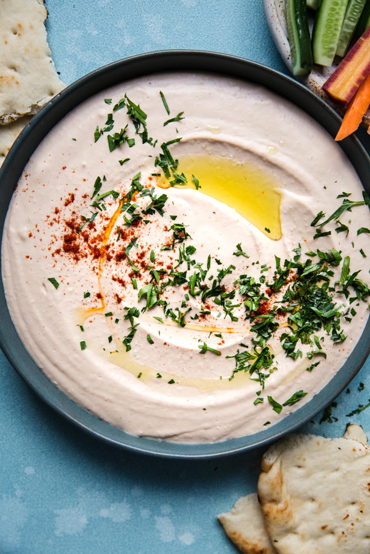 homemade White Bean Hummus in a bowl with paprika, olive oil and parsley served with pita