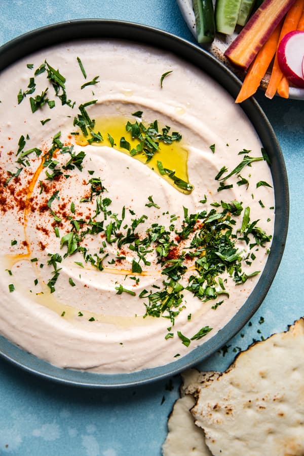 homemade White Bean Hummus in a bowl with paprika, olive oil and parsley