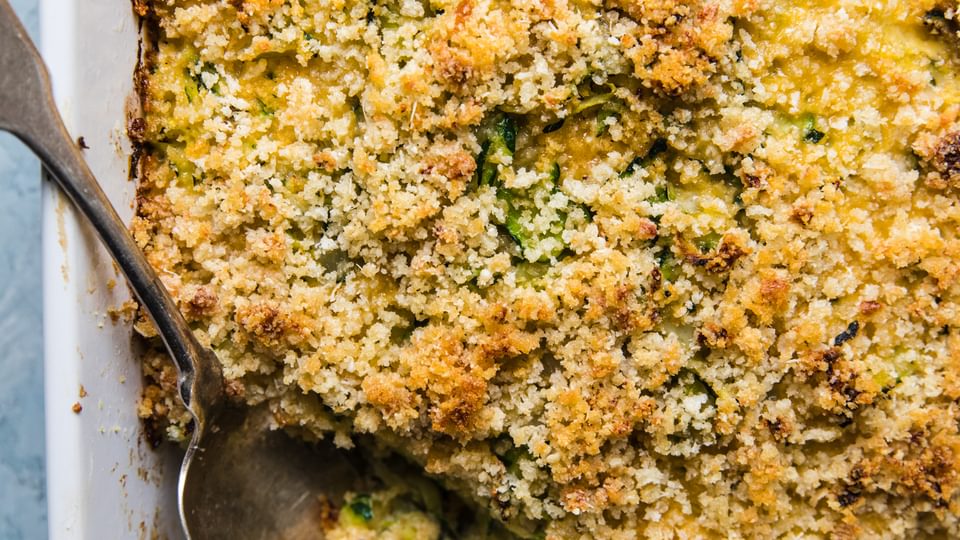 zucchini bake made with onions, dijon, garlic, parmesan, eggs, gruyere cheese, panko bread crumbs and butter