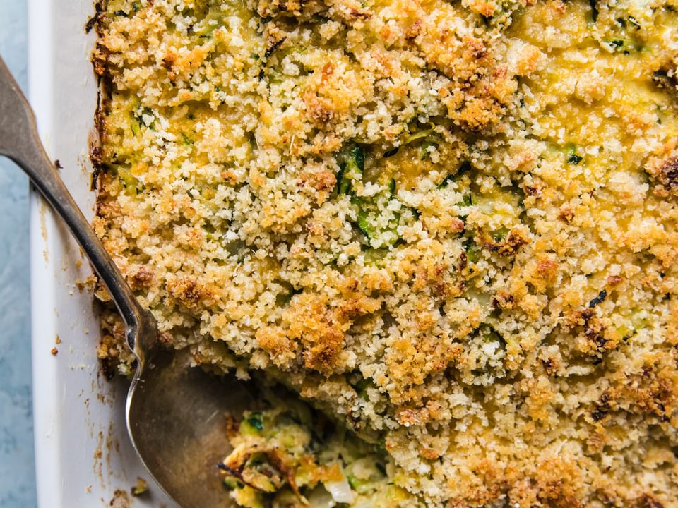 zucchini bake made with onions, dijon, garlic, parmesan, eggs, gruyere cheese, panko bread crumbs and butter