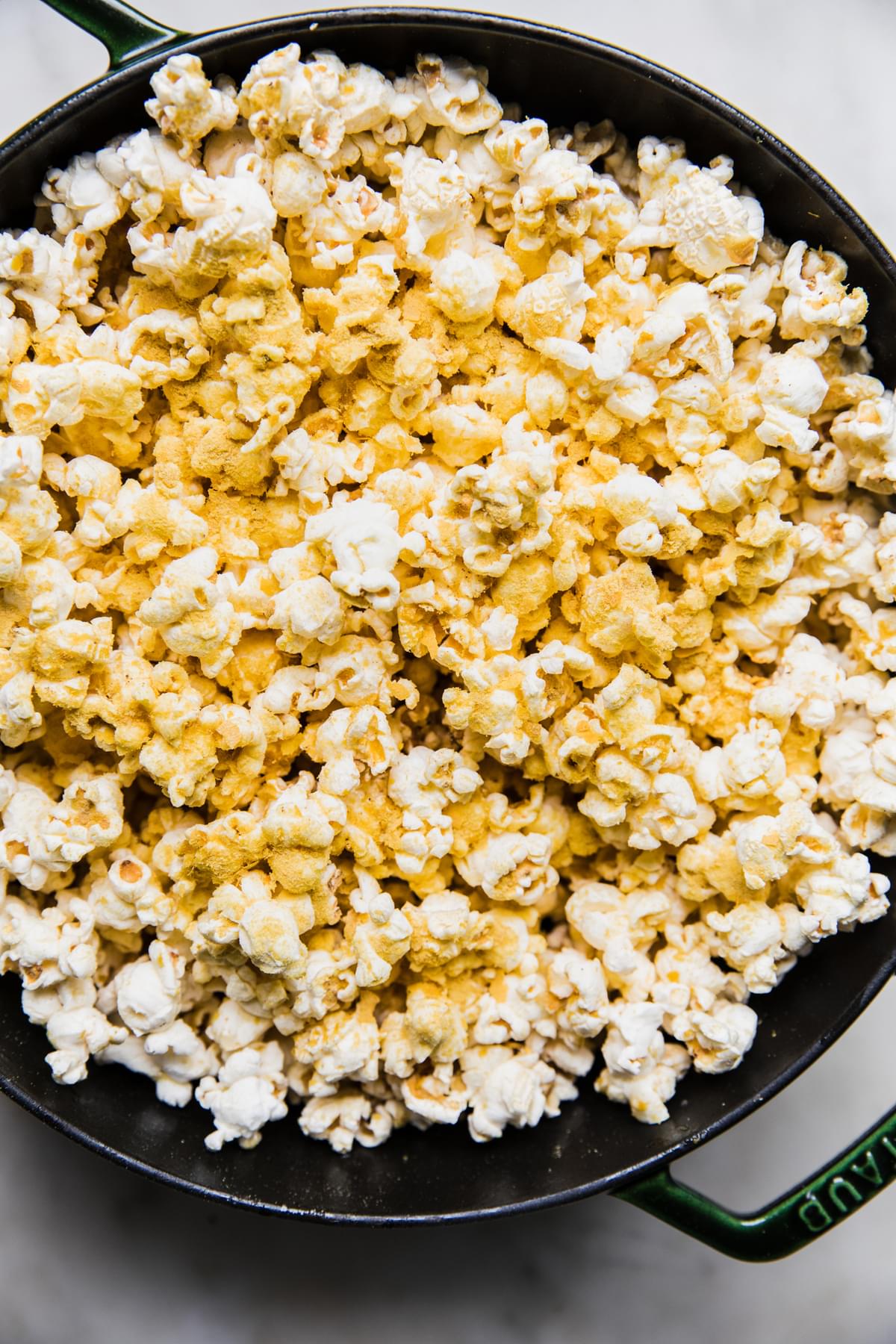 a dutch oven full of homemade popcorn seasoned with butter, salt and nutritional yeast