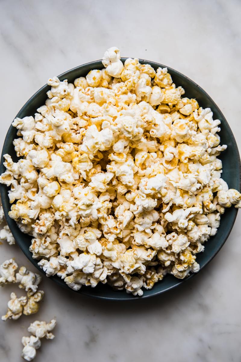 a bowl of homemade popcorn seasoned with butter, salt and nutritional yeast on the counter