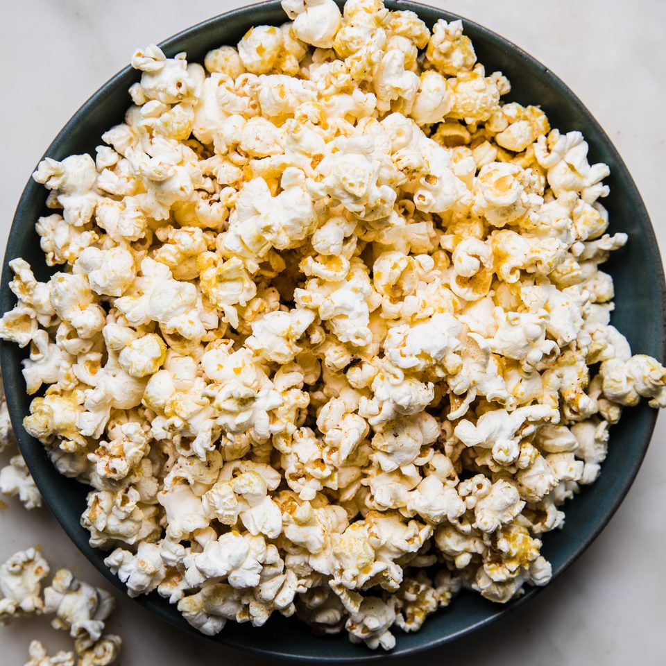 a bowl of homemade popcorn seasoned with butter, salt and nutritional yeast on the counter