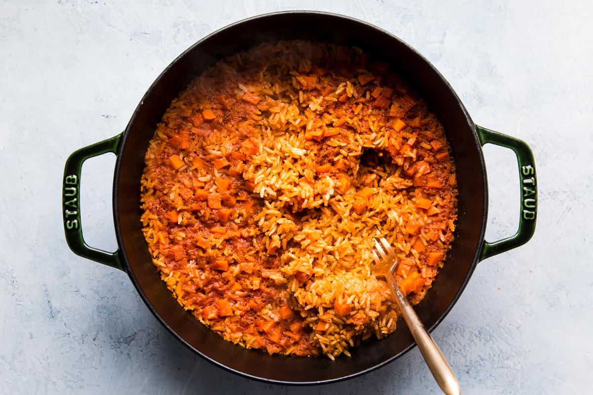 restaurant style Mexican rice shown in a large pot being fluffed with a fork.