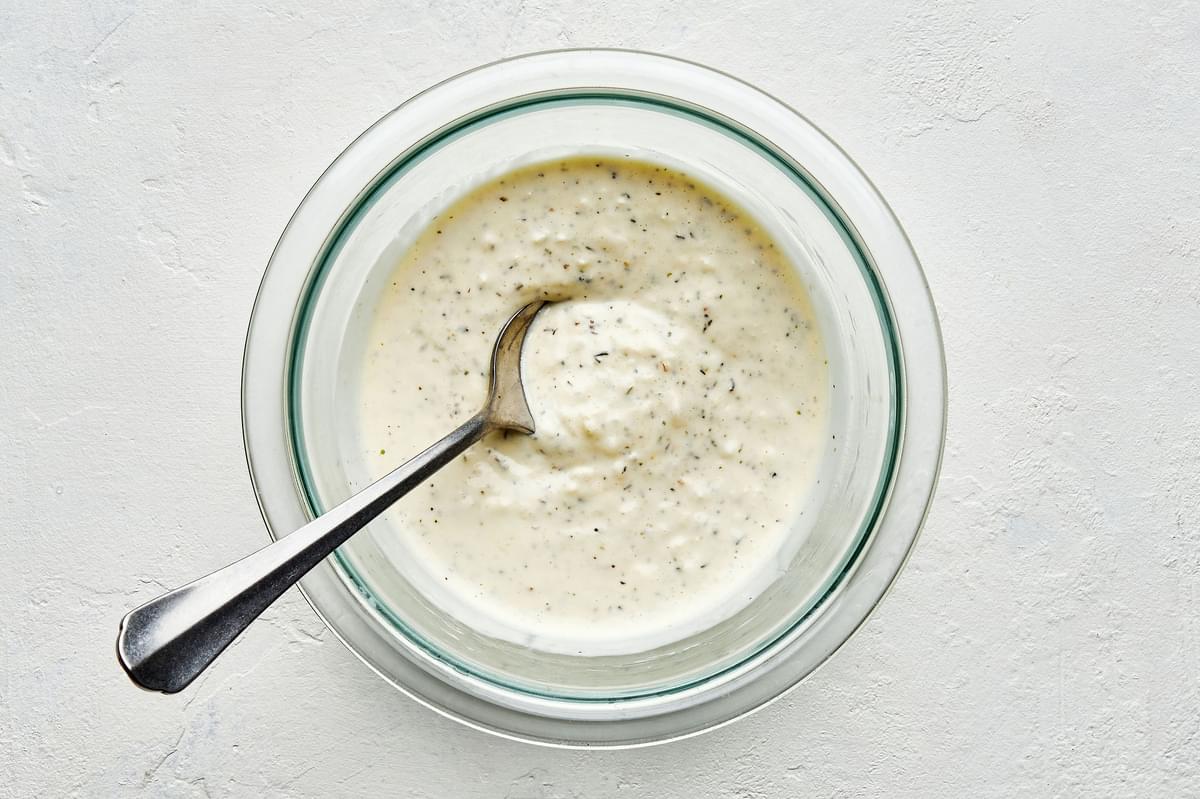 a bowl of homemade creamy parmesan lemon dressing made with lemon juice, olive oil, parmesan, mayo, dijon and spices