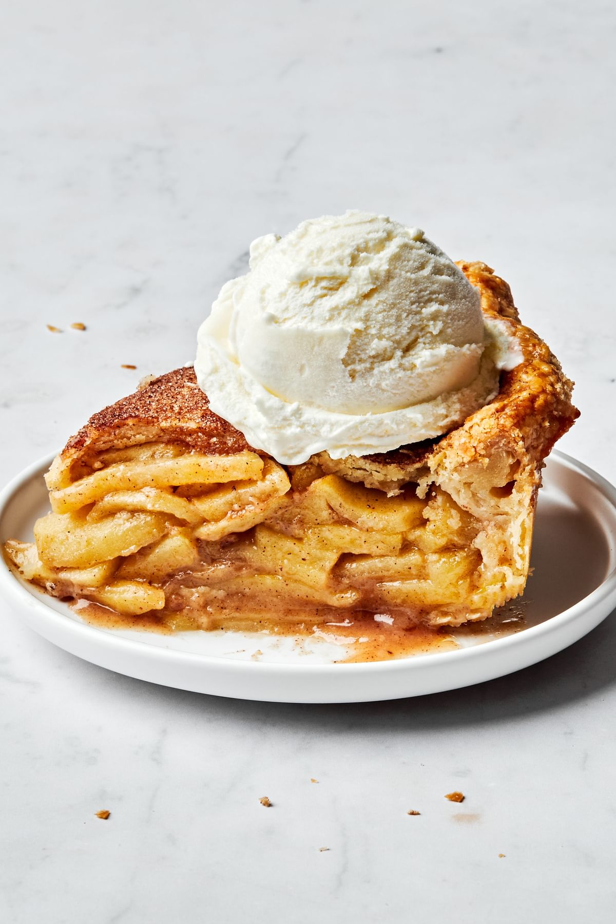 a slice of homemade apple pie topped with vanilla ice cream. Pie is seasoned with brown sugar, cinnamon and nutmeg.