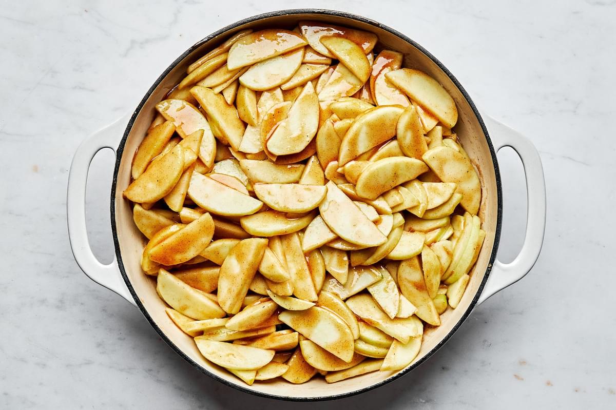 sliced, peeled apples being tossed in a pot with apple pie filling made with butter, flour, sugar, brown sugar and spices