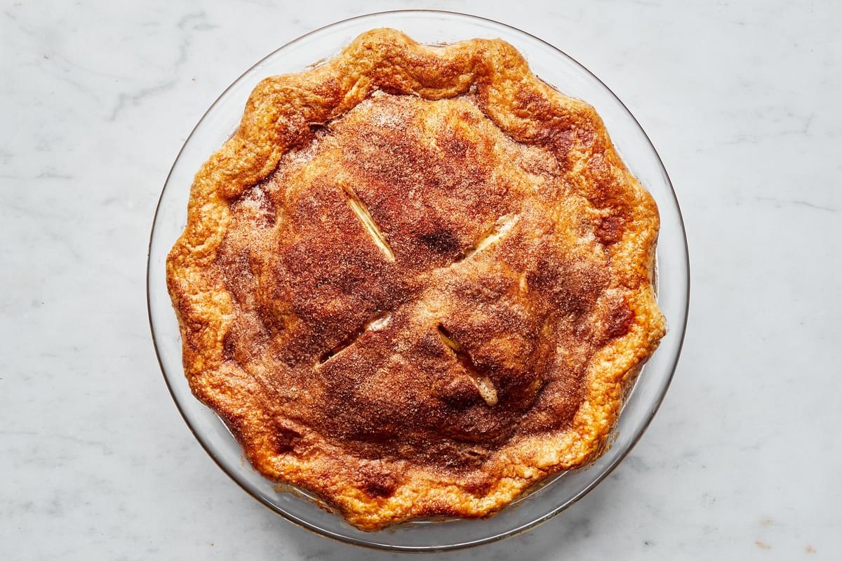 a simple homemade apple pie right out of the oven with golden brown flaky crust and topped with cinnamon and sugar