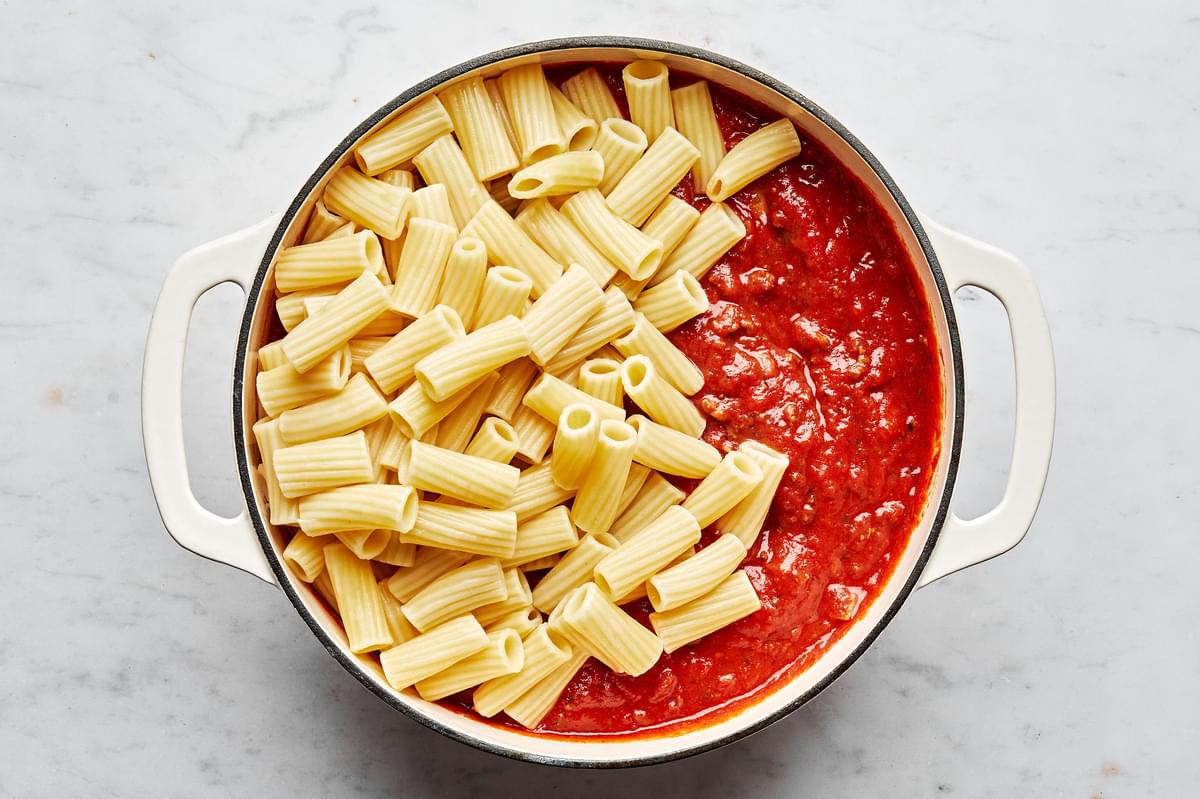ground beef, italian sausage, marinara butter, spices and rigatoni in a soup pot for making baked rigatoni