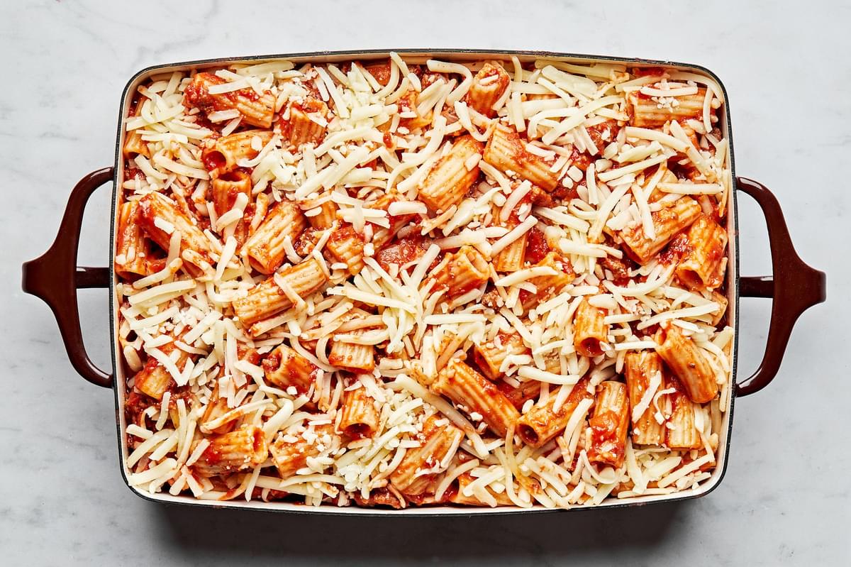 rigatoni with marinara sauce, italian sausage and ground beef topped with shredded mozzarella in a 9x13 casserole dish