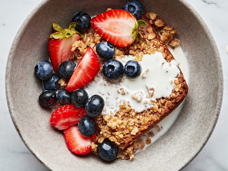 a slice of baked oatmeal seasoned with maple, cinnamon & nutmeg drizzled with milk and topped with fresh berries