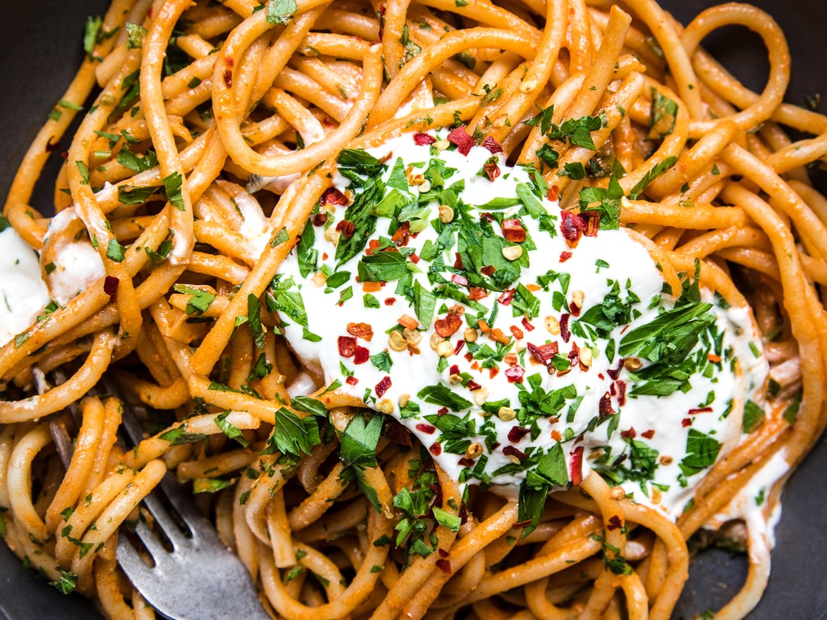 spicy roasted red pepper sauce with whipped feta on top of bucatini pasta sprinkled with red pepper flakes and fresh parsley