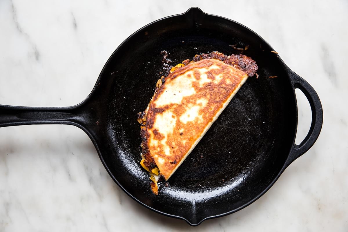 a butternut squash quesadilla with caramelized onion being fried in vegetable oil in a skillet
