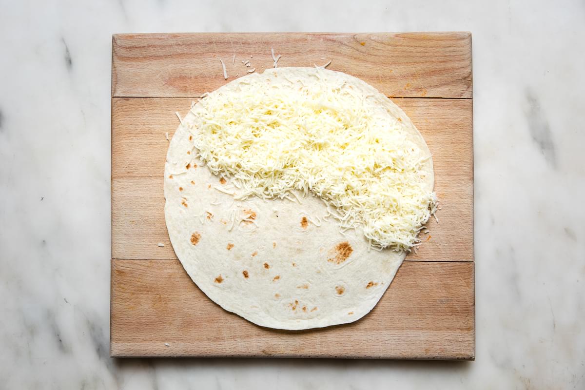 a flour tortilla with organics shredded mozzarella cheese  on half of it