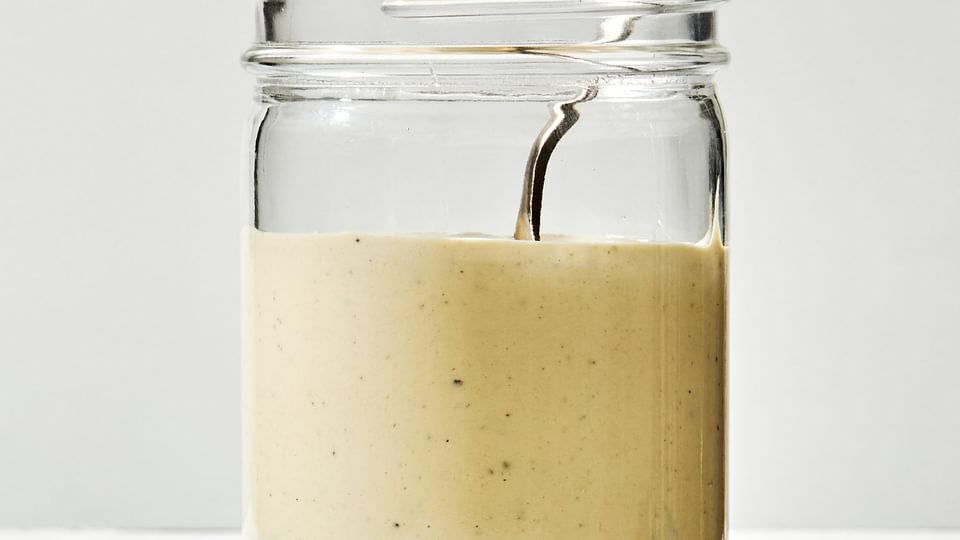 homemade Caesar dressing made with egg yolk, anchovy, garlic, lemon, salt, avocado oil Worcestershire and pepper in a jar
