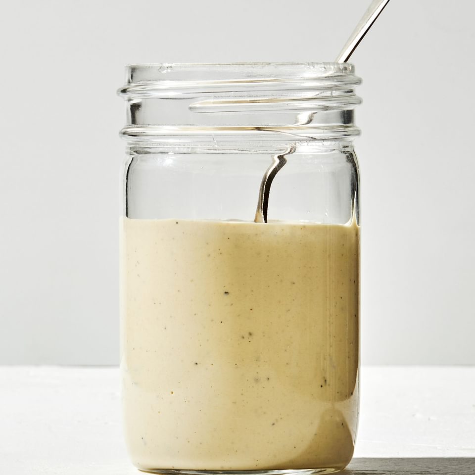 homemade Caesar dressing made with egg yolk, anchovy, garlic, lemon, salt, avocado oil Worcestershire and pepper in a jar