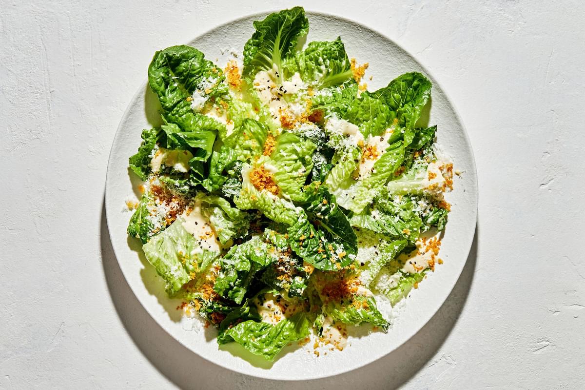 caesar salad with homemade caesar dressing, finely grated parmesan, toasted breadcrumbs and black pepper on a plate