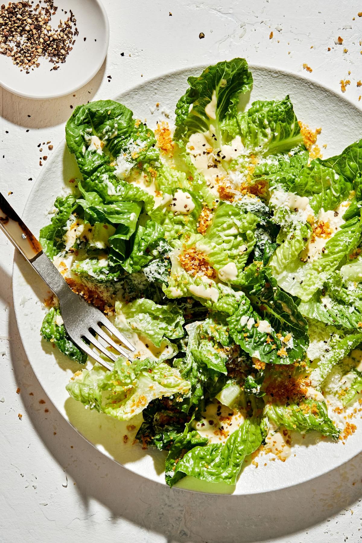 Caesar salad with homemade caesar dressing, toasted breadcrumbs and grated Parmesan cheese on a plate with a fork
