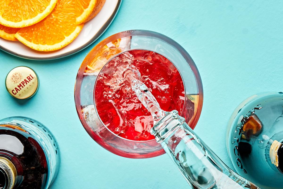 prosecco being poured into a glass with ice and campari to make a campari spritz
