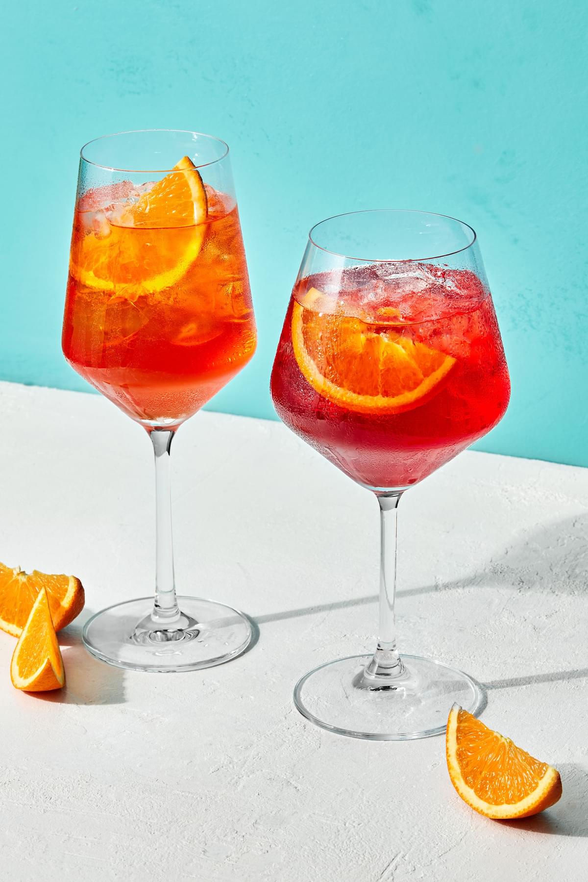 2 glasses of  campari spritz made with prosecco, Campari, sparkling water with  orange wedges for garnish