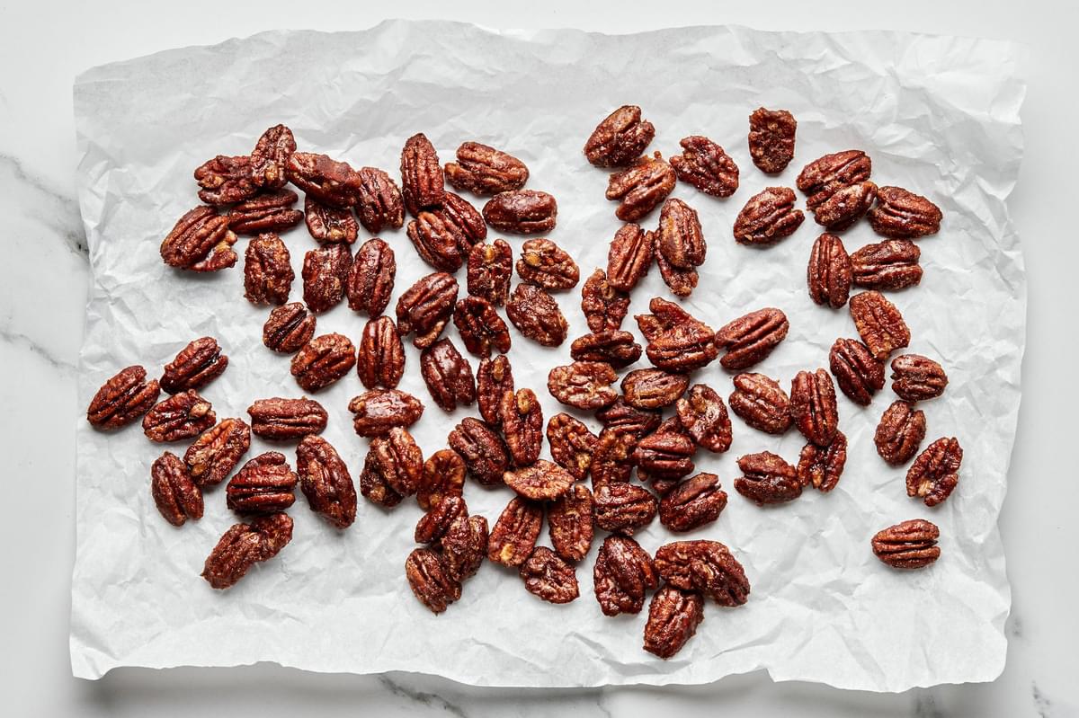 homemade candied pecans made with brown sugar, cinnamon, salt and cayenne pepper cooling on a piece of parchment paper