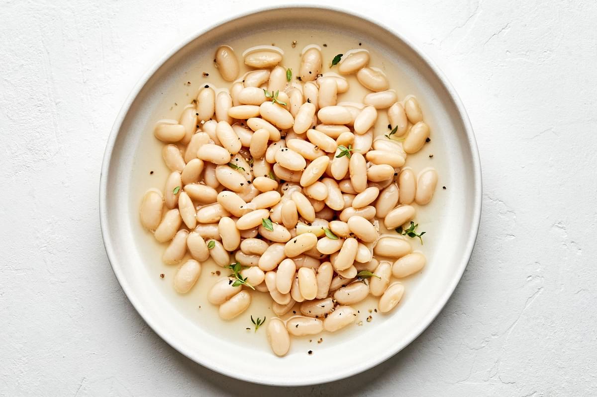 homemade cannellini beans made with onion, bay leaves, thyme, garlic, salt & pepper in a bowl