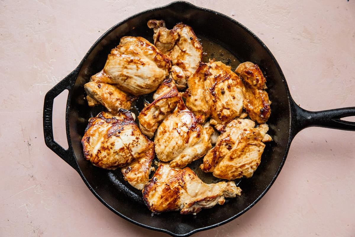 marinated chicken adobo chicken thighs being browned in a skillet