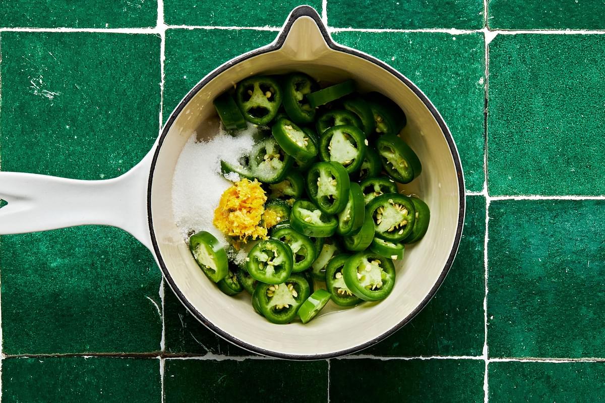 sliced jalapeño, sugar and lemon zest in a pot for making candied jalapeños for chicken burgers