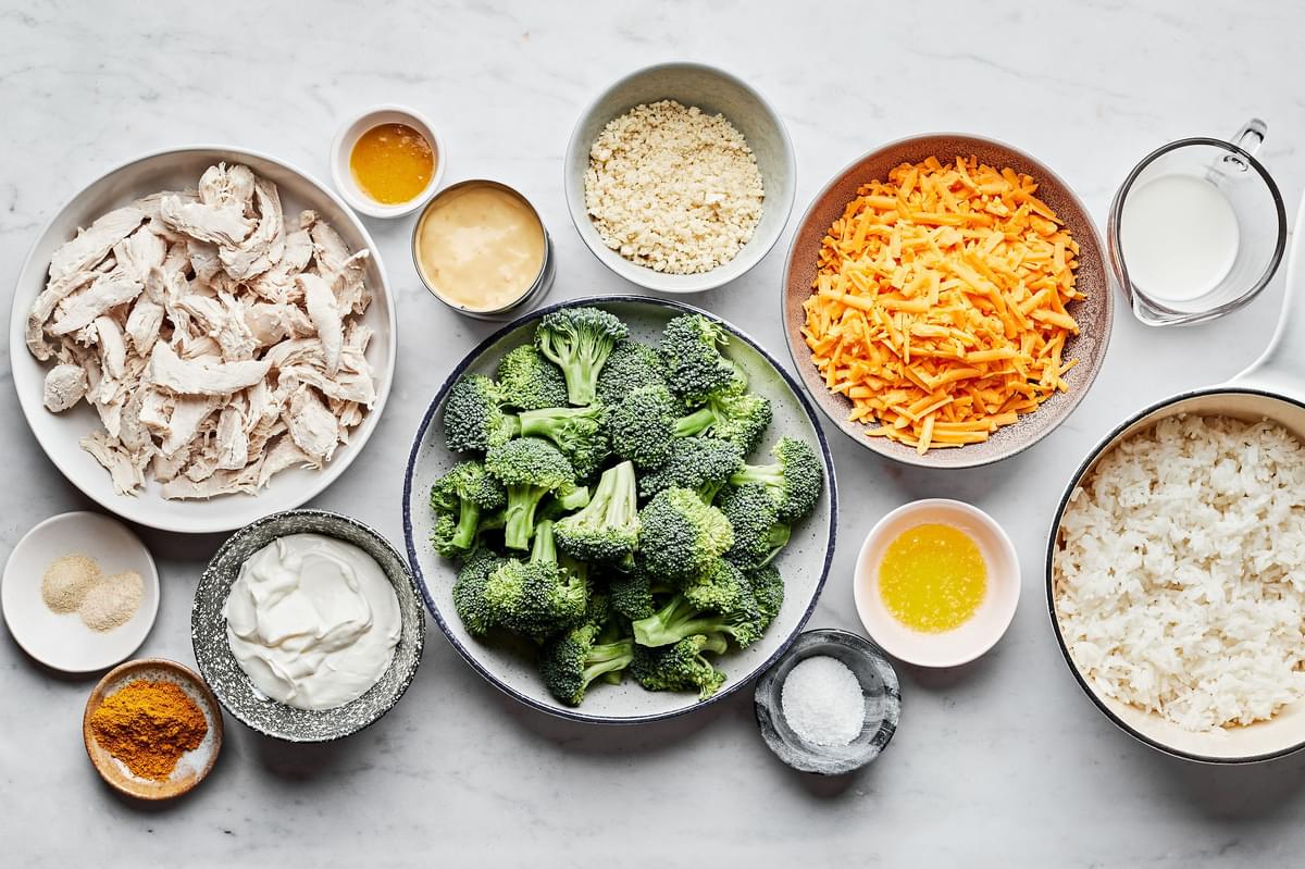 raw broccoli, chicken, cheese, cream of chicken soup, milk, sour cream, spices and panko in bowls for chicken divan
