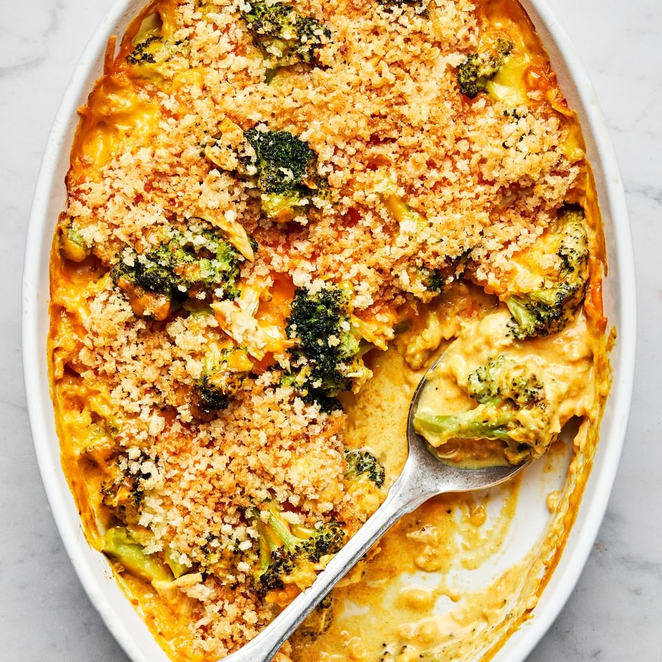 chicken divan in a casserole dish with a serving spoon made with chicken, broccoli, cheese and topped with panko