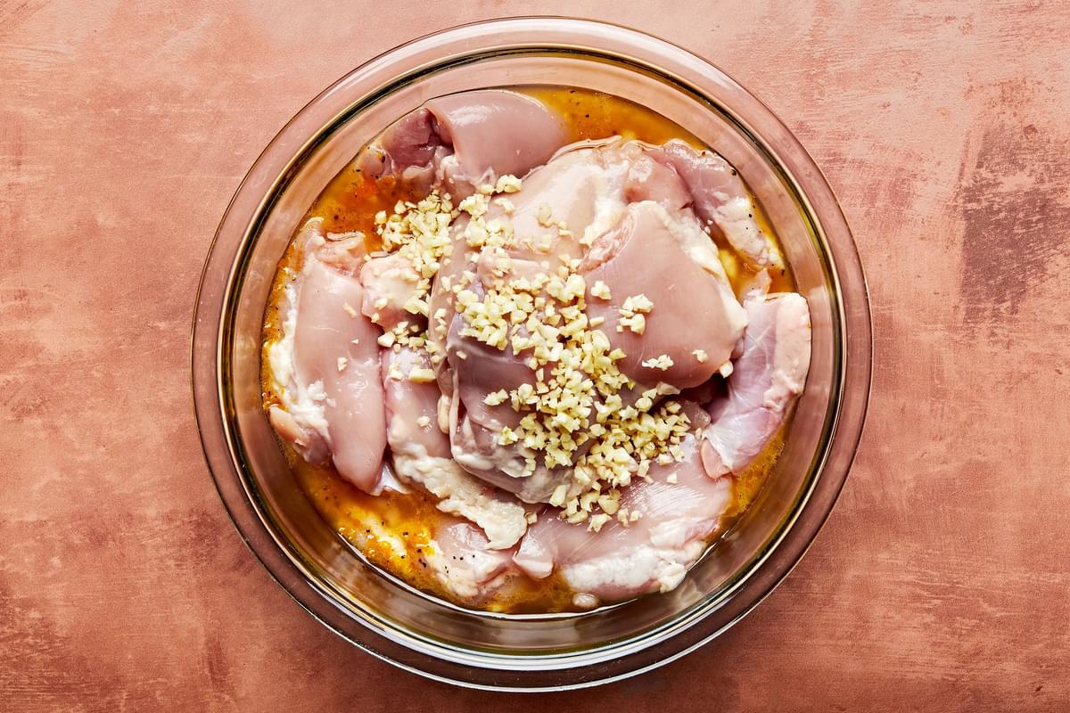 raw chicken in a bowl of homemade marinade made with vegetable oil, orange zest, orange juice, honey, salt, and pepper