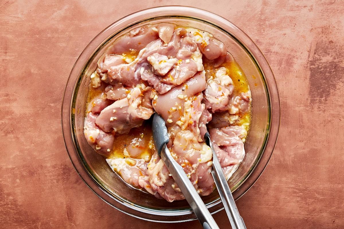 raw chicken in a bowl of homemade marinade made with vegetable oil, orange zest, orange juice, honey, salt, and pepper