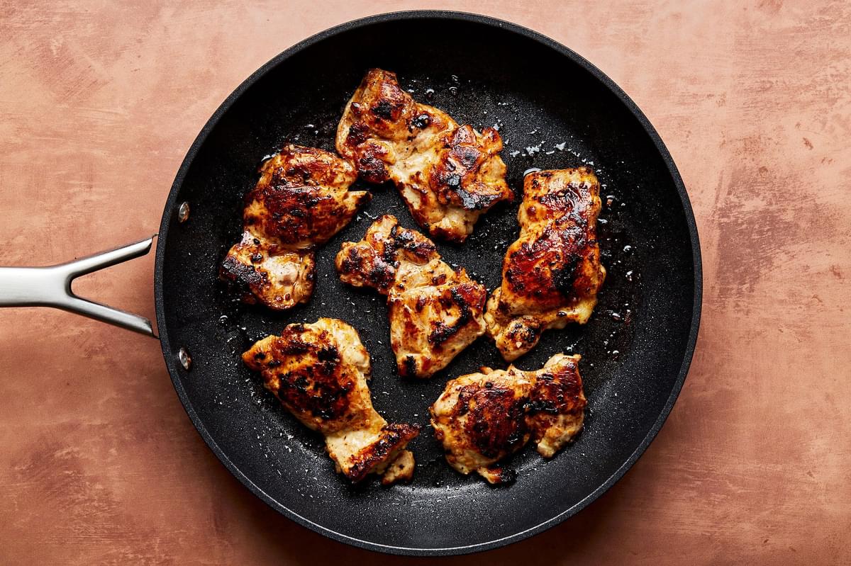 boneless, skinless, chicken thighs being cooked in a skillet that have been marinated in a homemade citrus sauce