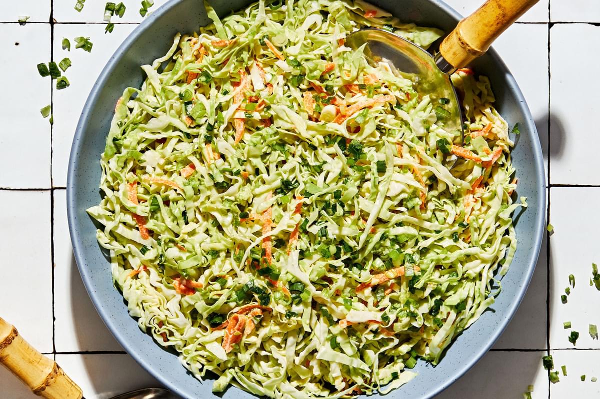homemade classic coleslaw in a serving bowl with a wooden serving spoon on the counter