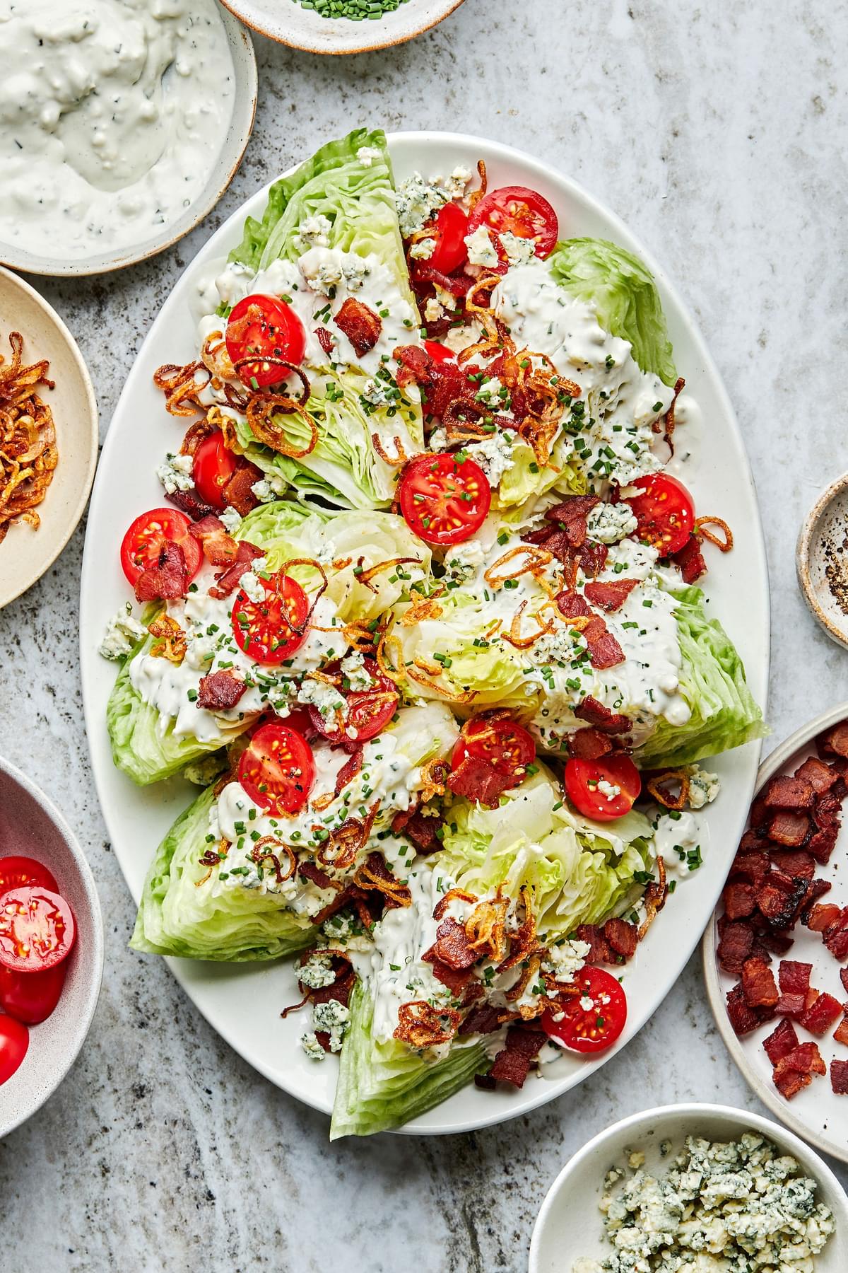 a platter of classic wedge salads with homemade blue cheese dressing, bacon, tomatoes & fried shallots surrounded by toppings