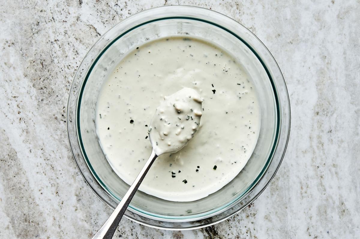 homemade blue cheese dressing in a bowl with a spoon to be put on top of classic wedge salads