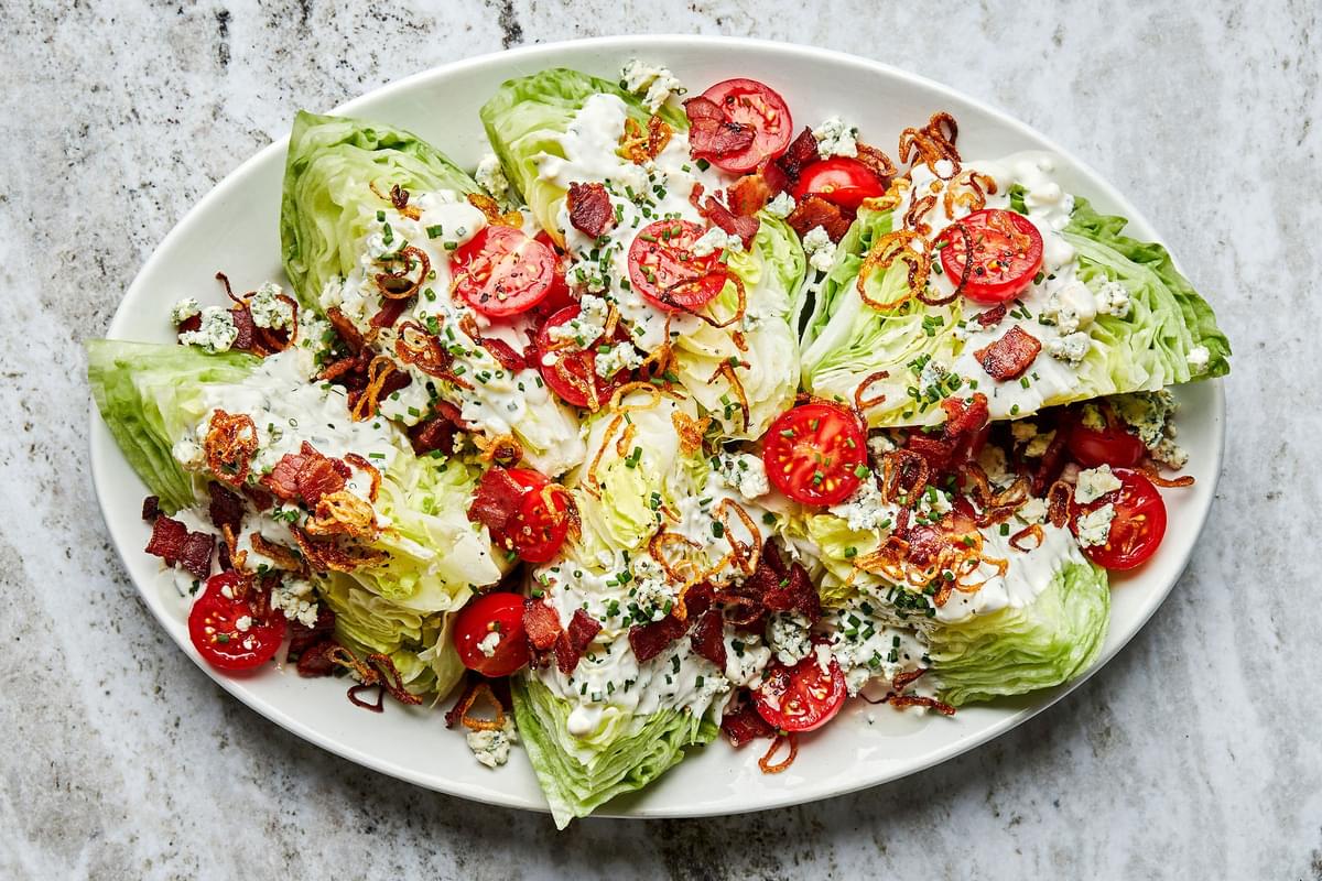 a platter of classic wedge salads with homemade blue cheese dressing, blue cheese, cherry tomatoes, bacon and fried shallots