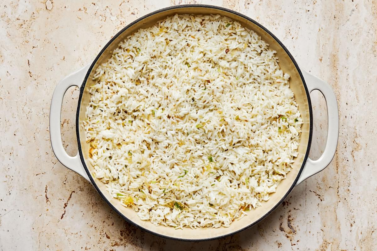 coconut rice, white and light green onions, coconut flakes and ginger being cooked in coconut oil in a pan